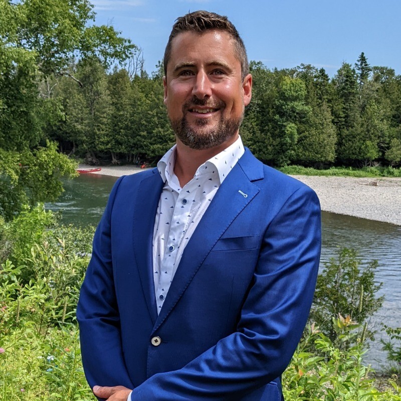 Portrait de Jean-François Paquin, fondateur, en complet bleu devant une rivière